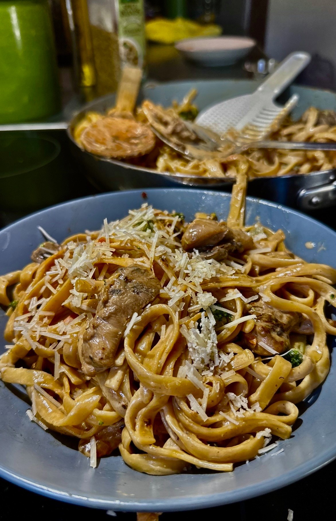 A bowl of penne in Parmesan cream sauce tossed with seared strips of grouse breast, red pepper, mushrooms, carrots, and zucchini, topped with basil ribbons and grated cheese.